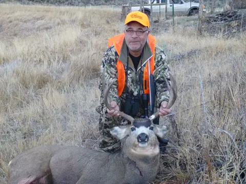 Hunter in blaze orange with a mule deer buck